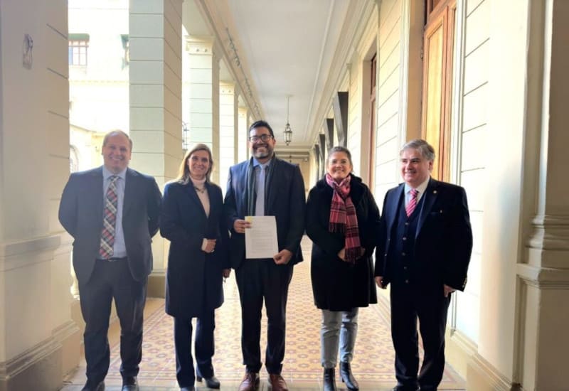 5 personas de frente. Al medio director escuela mostrando documentación firmada